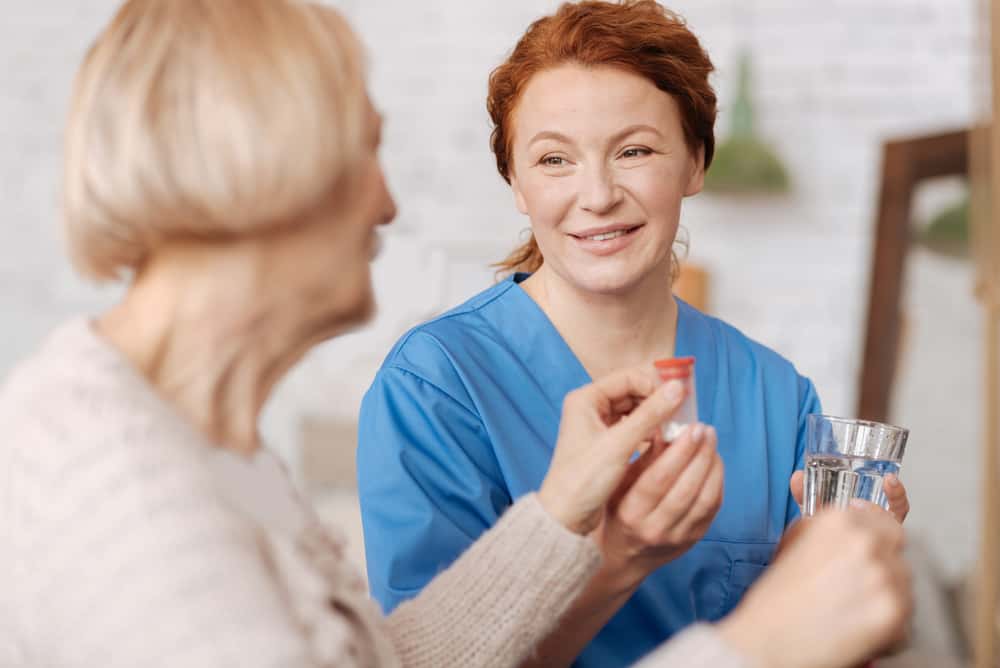 Nurse smiling with elderly patient in room